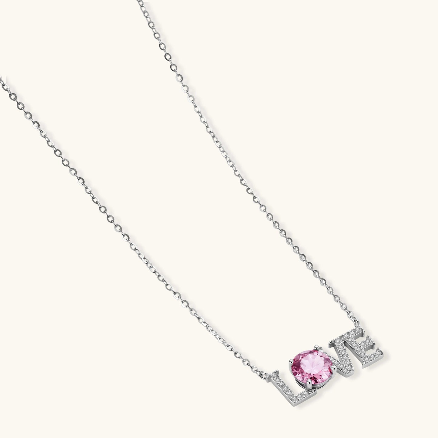 Sterling silver LOVE necklace with pink moissanite stone replacing the O, featuring crystal-set letters on delicate chain.