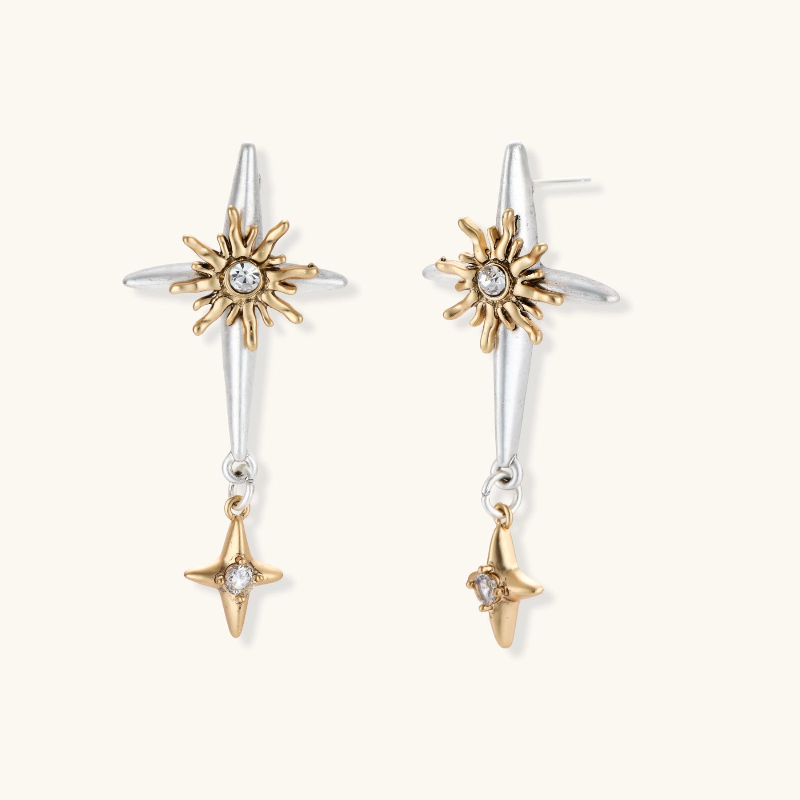 Dangle earrings with silver hoops, gold sun charms with crystals, and gold four-pointed star drops on cream background.