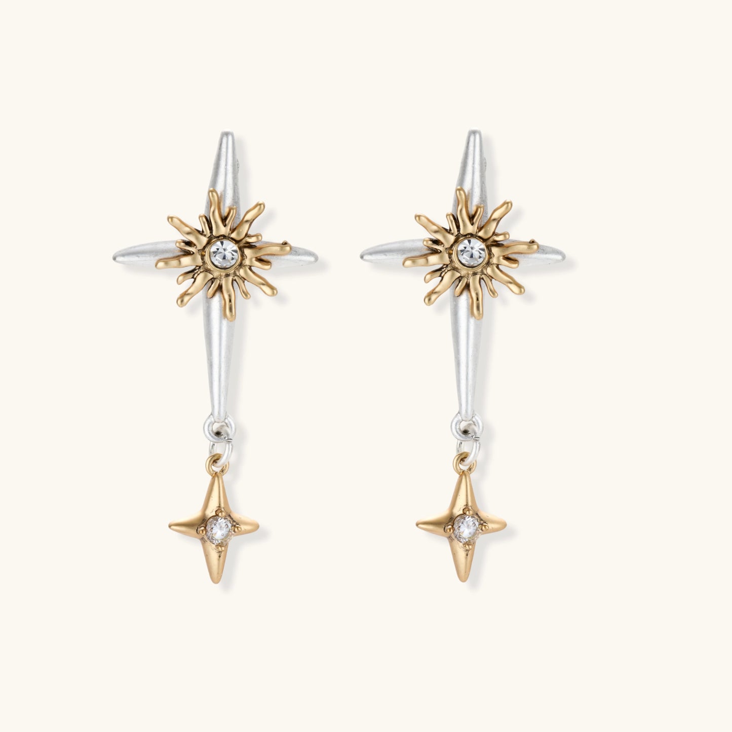Dangle earrings with silver hoops, gold sun charms with crystals, and gold four-pointed star drops on cream background.