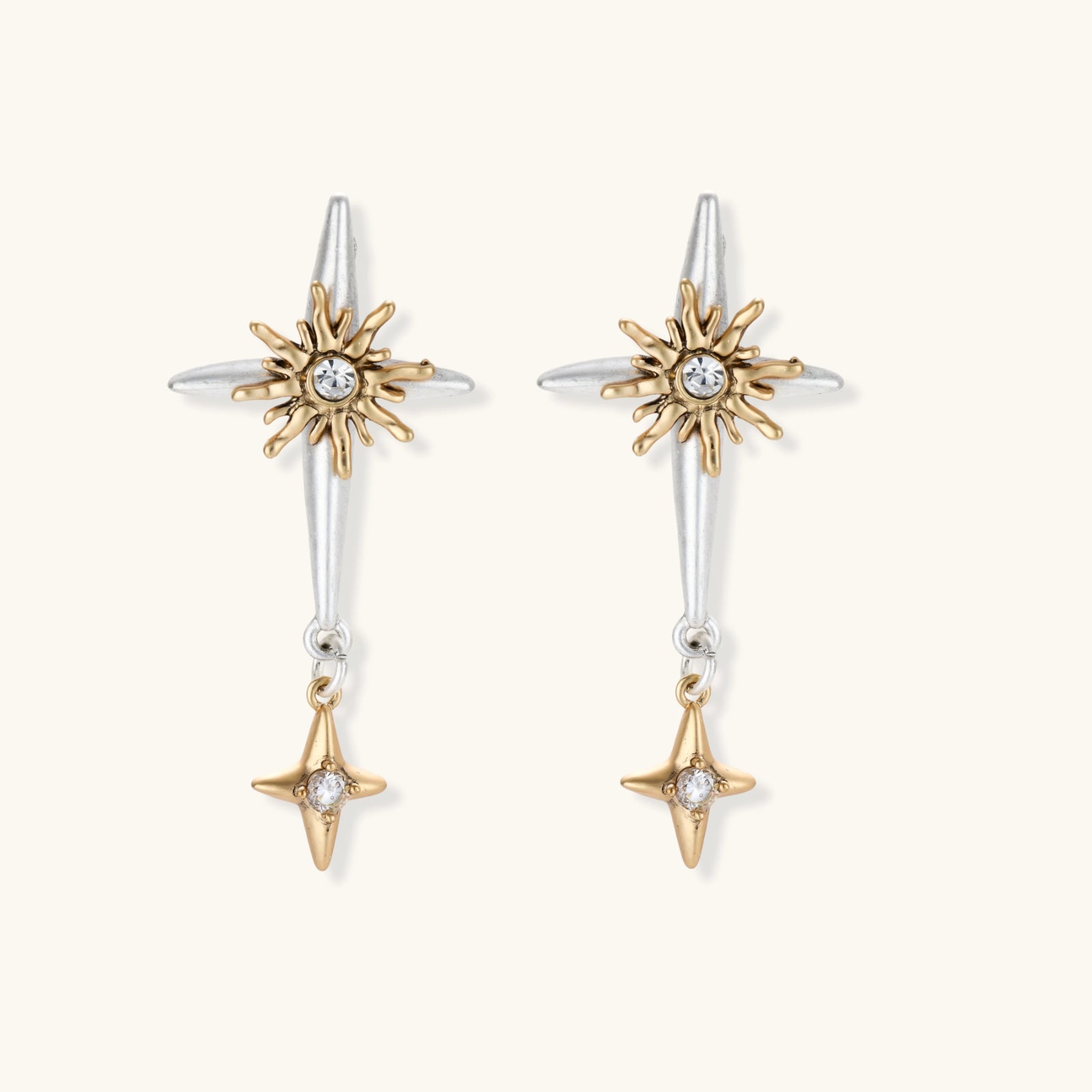 Dangle earrings with silver hoops, gold sun charms with crystals, and gold four-pointed star drops on cream background.
