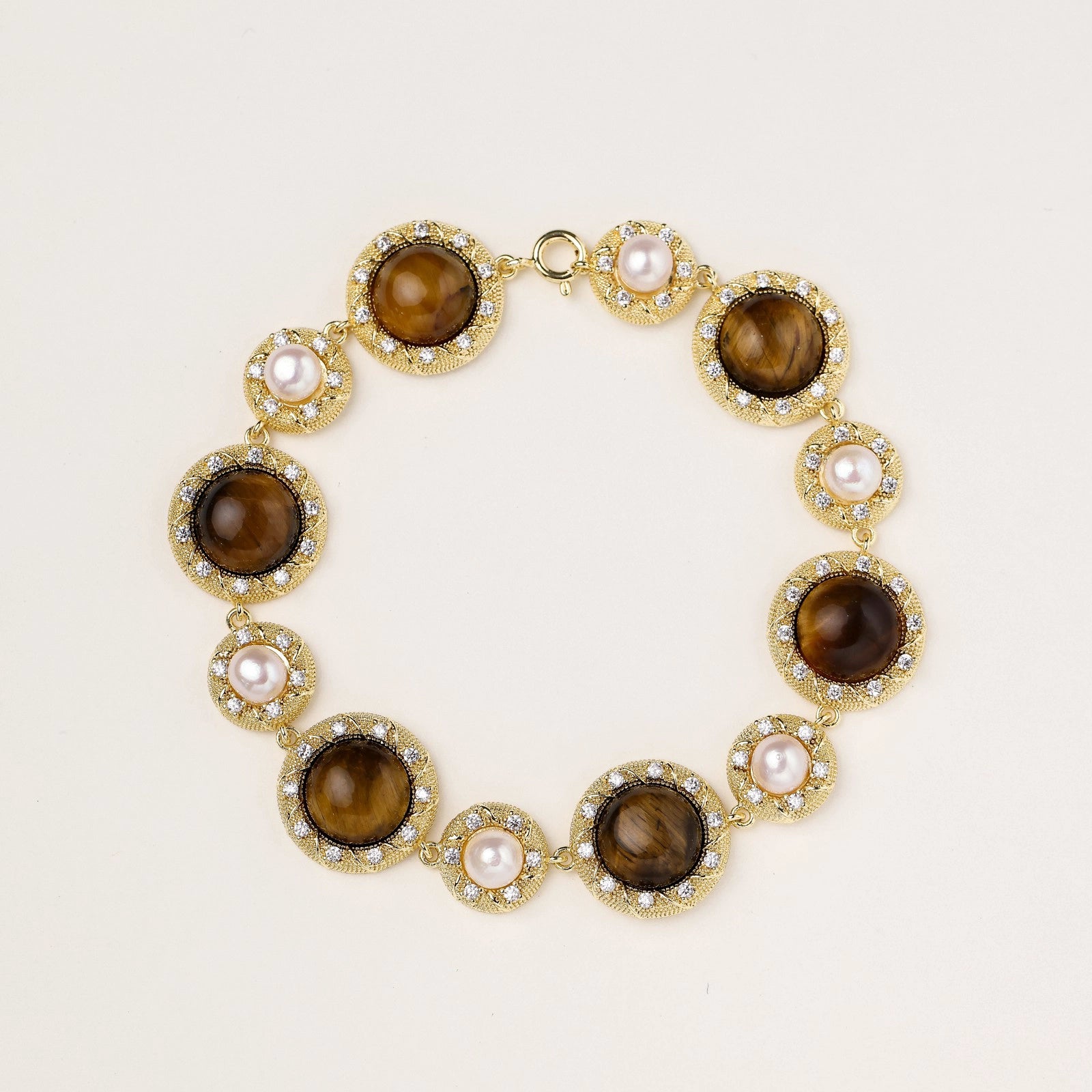 Gold-plated link bracelet with alternating brown tiger's eye stones and white freshwater pearls in ornate bezels.