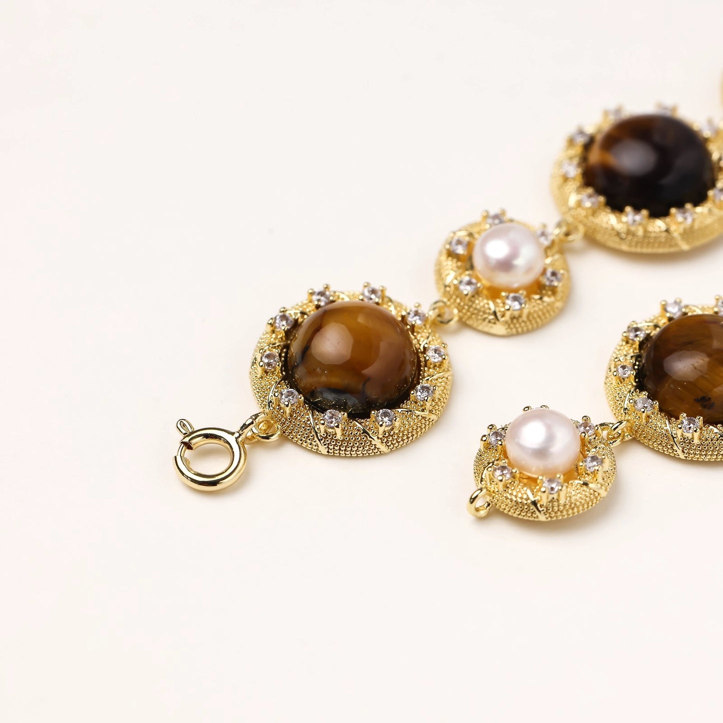 Gold-plated link bracelet with alternating brown tiger's eye stones and white freshwater pearls in ornate bezels.