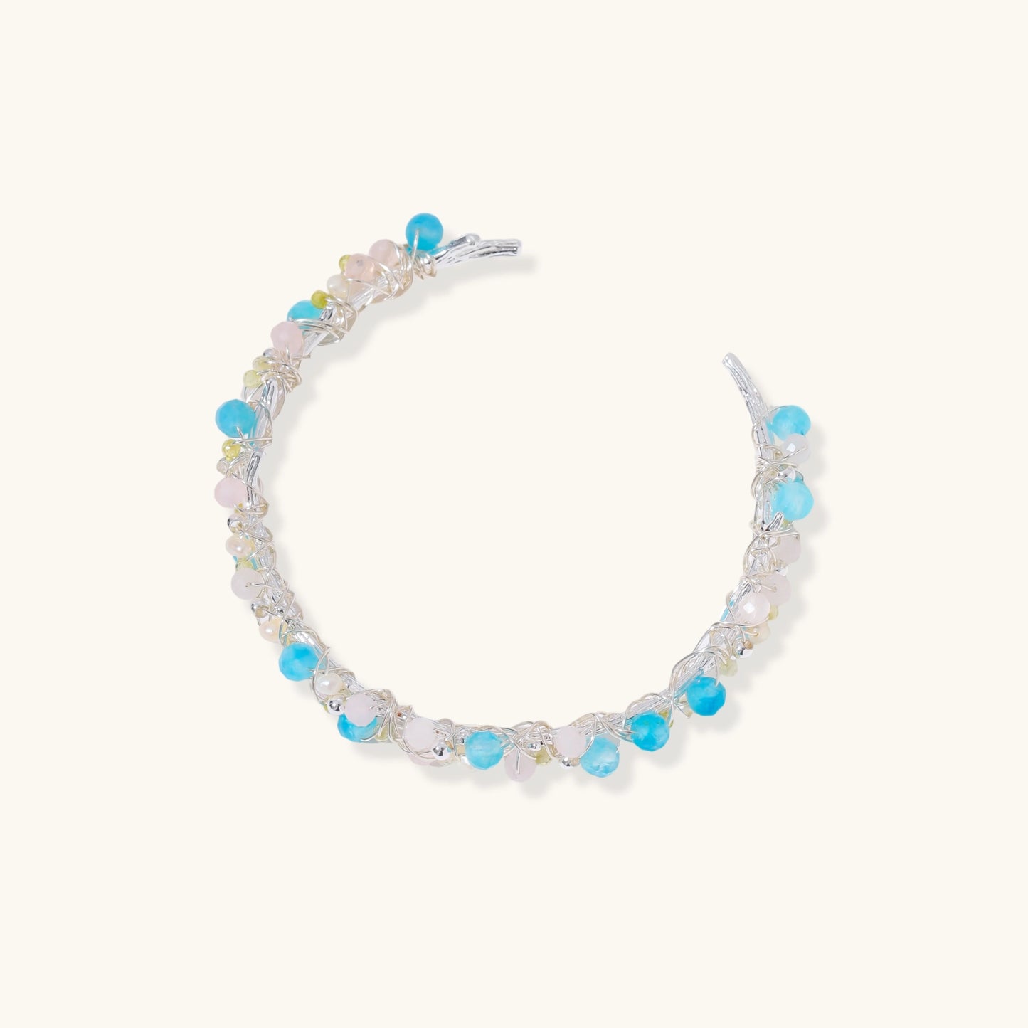 Delicate wire-wrapped bracelet featuring turquoise, rose quartz, freshwater pearls, and zircon on a white background.
