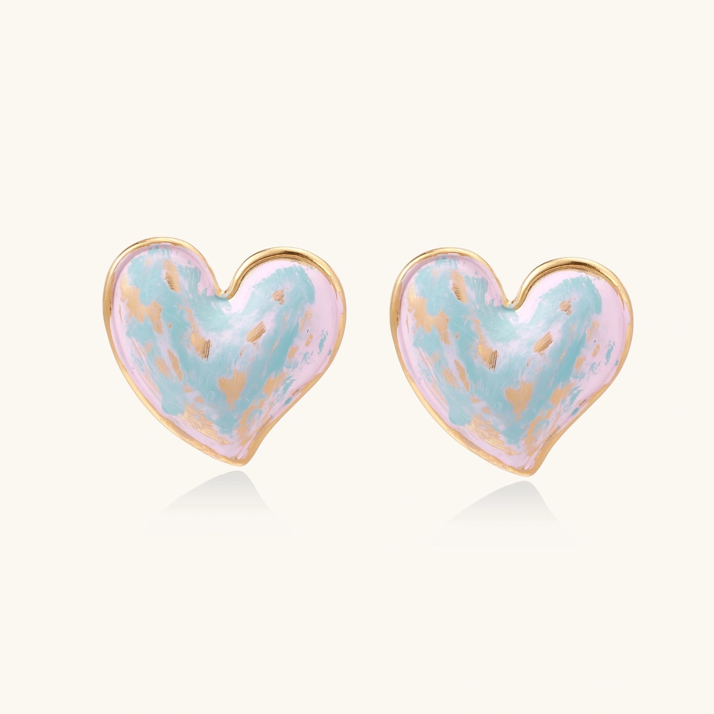 Heart-shaped stud earrings with swirled turquoise and pink enamel in gold-plated frames on cream background