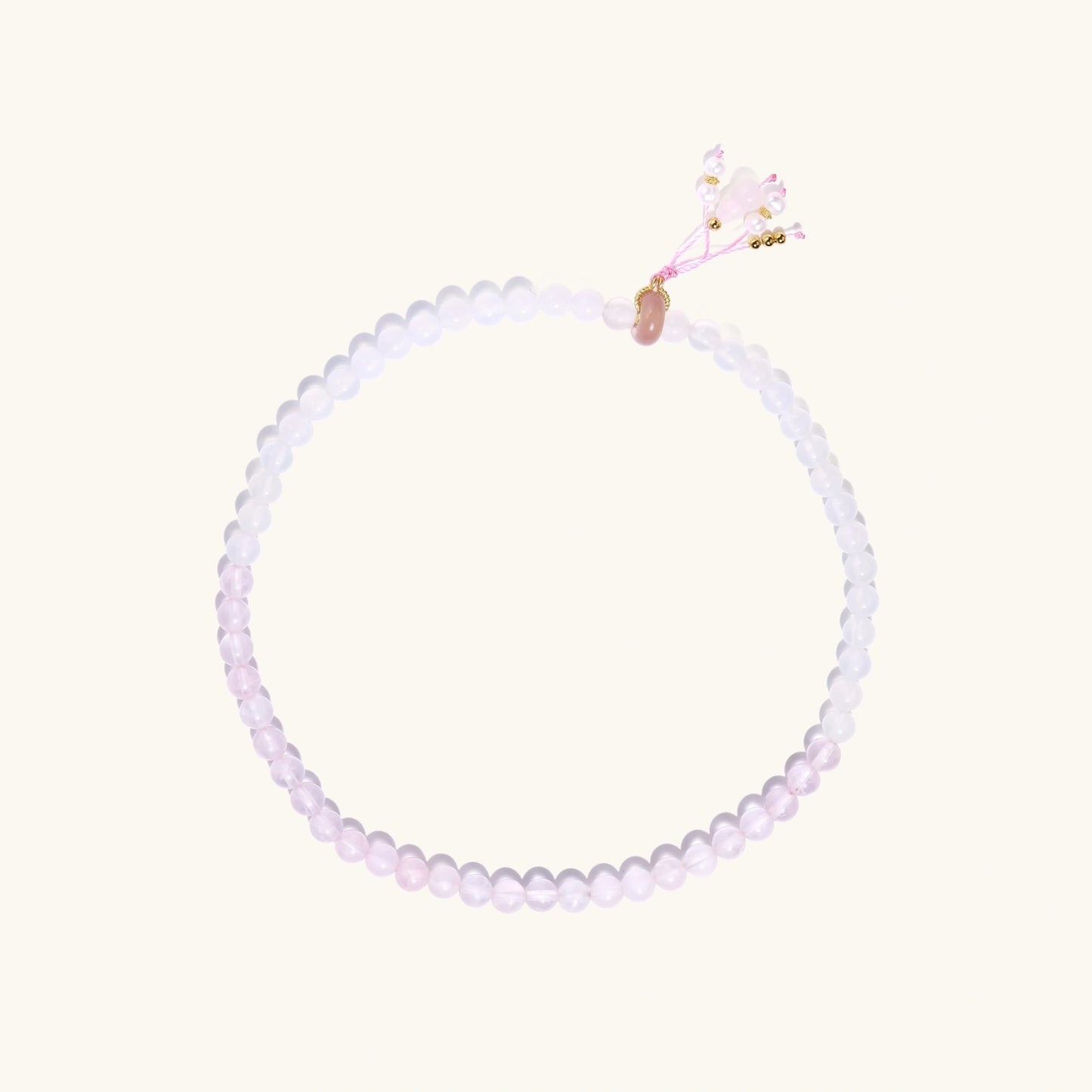 Double-wrap lavender beaded bracelet with rose quartz, pearls, gold vermeil charm and pink tassel on white background.