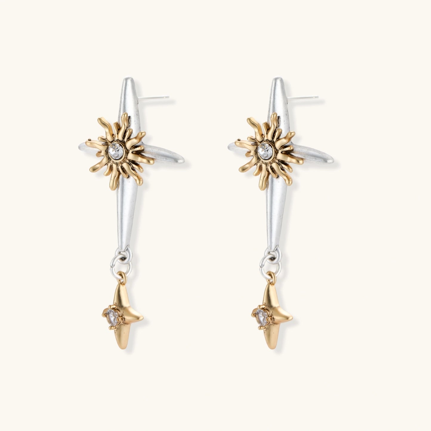 Dangle earrings with silver hoops, gold sun charms with crystals, and gold four-pointed star drops on cream background.