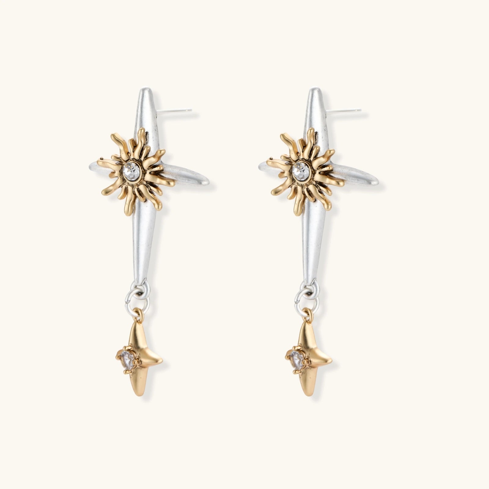 Dangle earrings with silver hoops, gold sun charms with crystals, and gold four-pointed star drops on cream background.