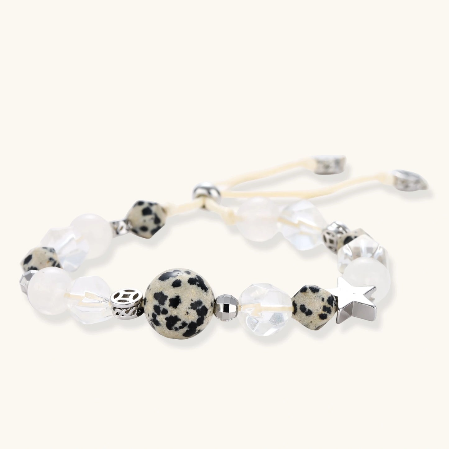 Adjustable beaded bracelet with spotted dalmatian stones, clear quartz crystals, and silver star charm on white background.