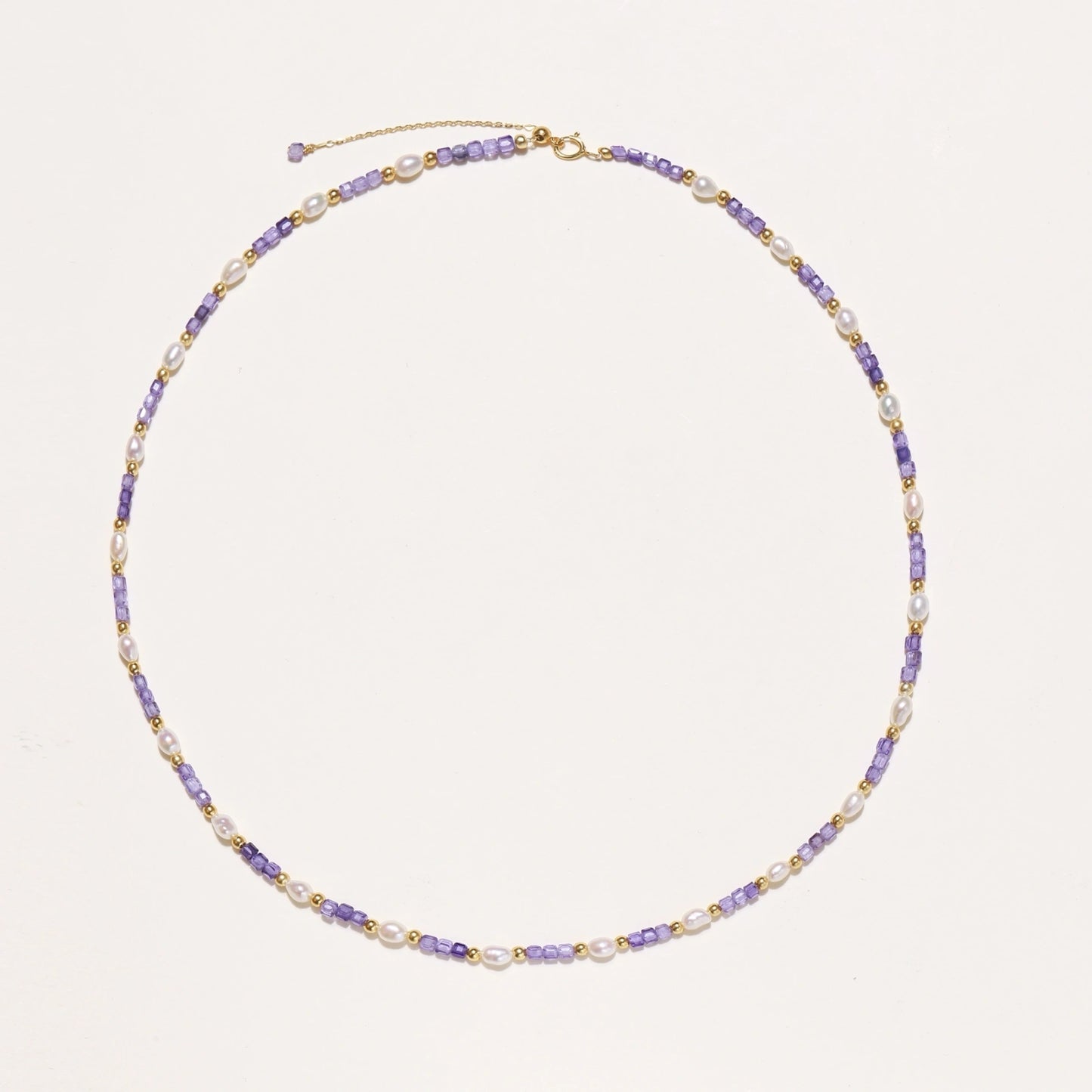 Delicate 18K gold vermeil necklace with alternating lavender zirconia beads and white freshwater pearls on cream background