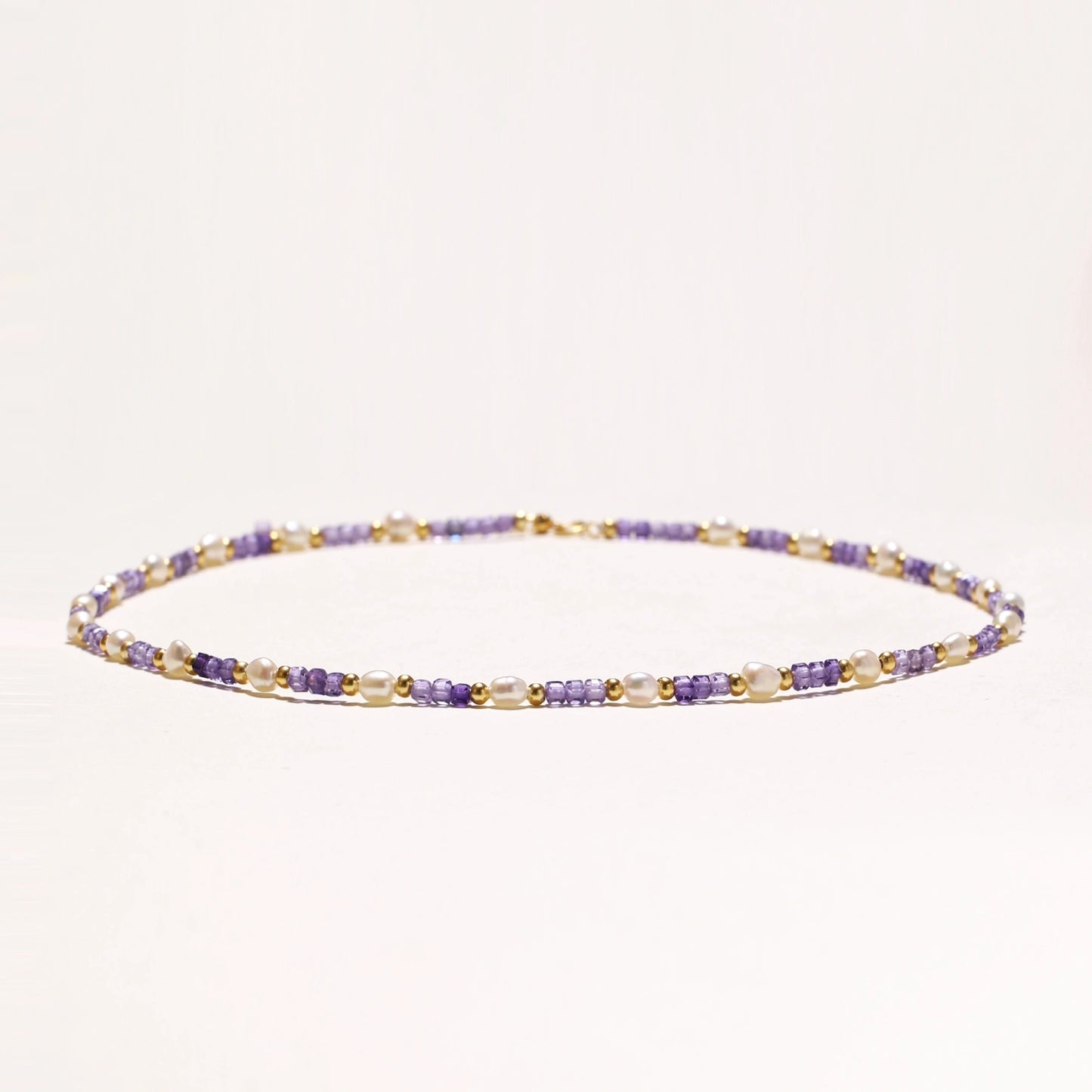 Delicate 18K gold vermeil necklace with alternating lavender zirconia beads and white freshwater pearls on cream background