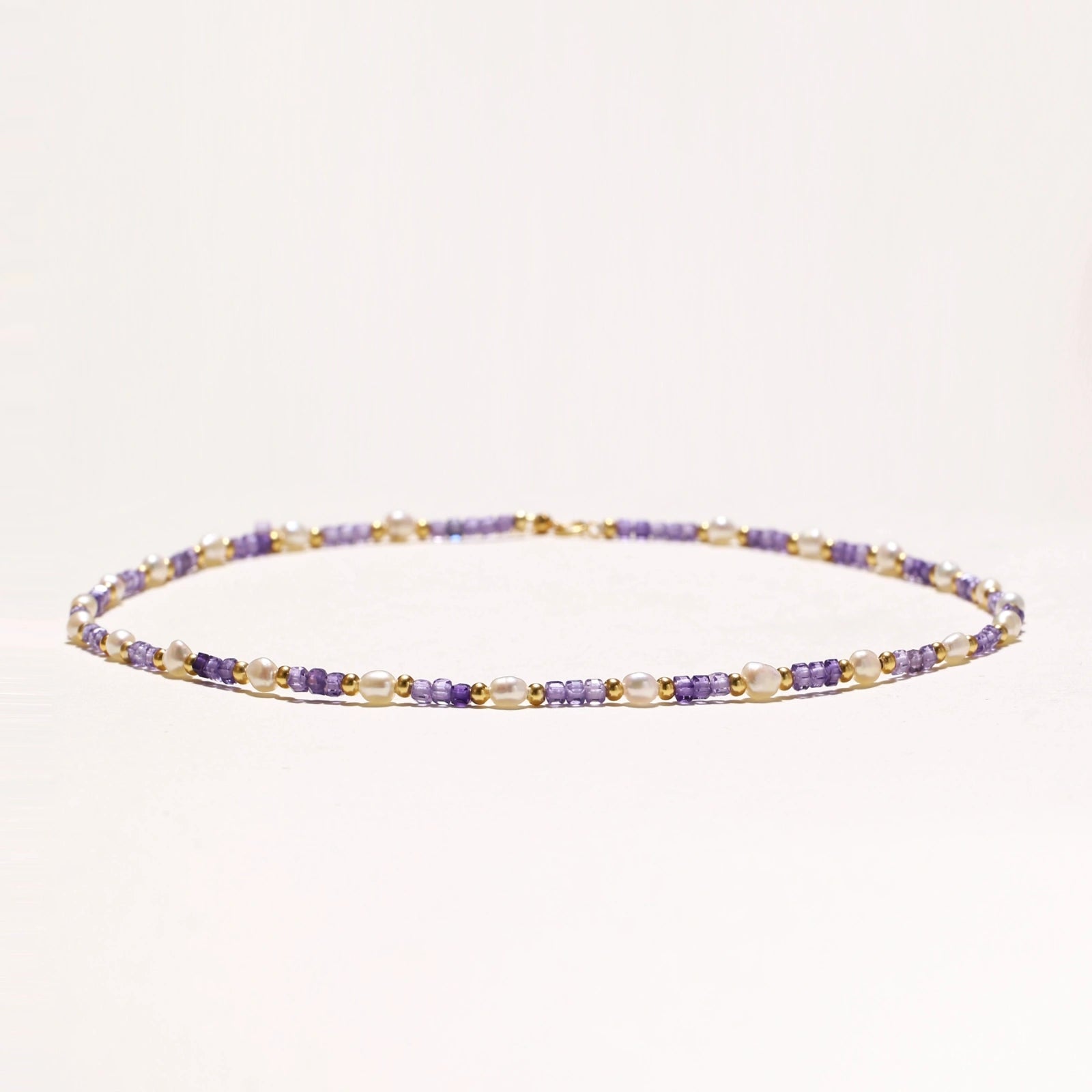 Delicate 18K gold vermeil necklace with alternating lavender zirconia beads and white freshwater pearls on cream background