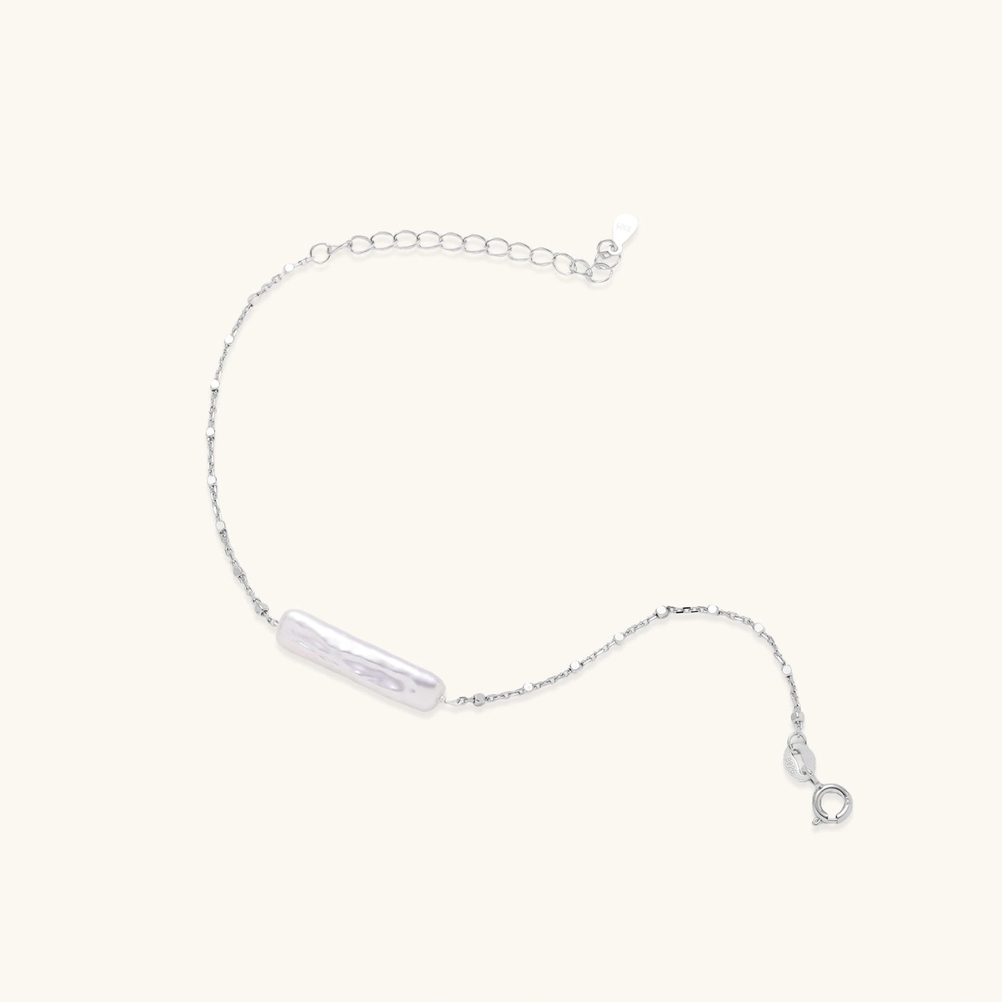 Minimalist bracelet with iridescent baroque pearl on rhodium-plated sterling silver chain against cream background