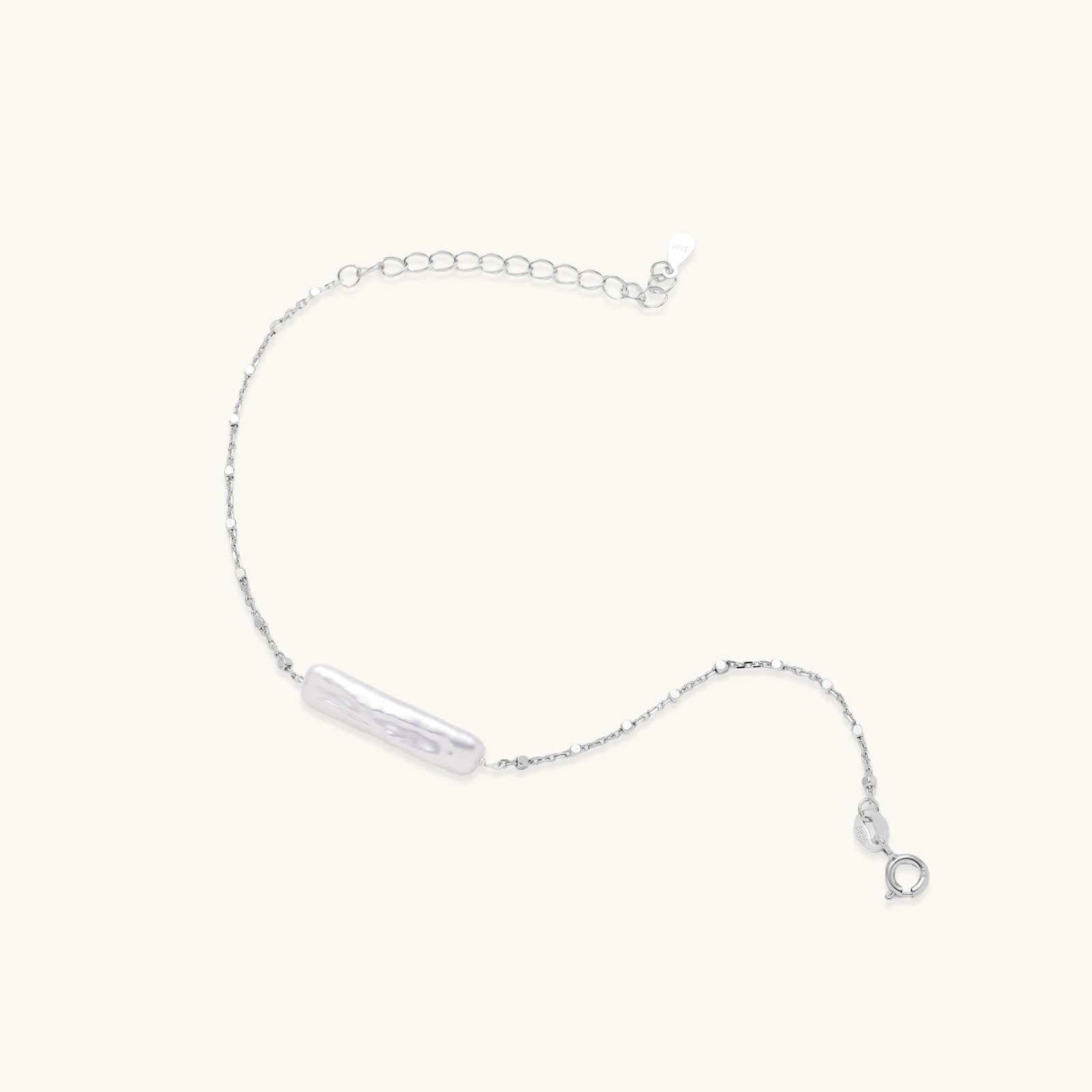Minimalist bracelet with iridescent baroque pearl on rhodium-plated sterling silver chain against cream background