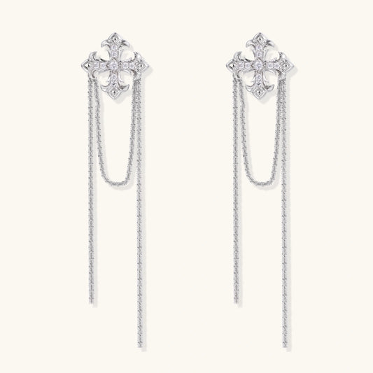 White gold plated baroque cross stud earrings with long cascading zirconia chains on cream background