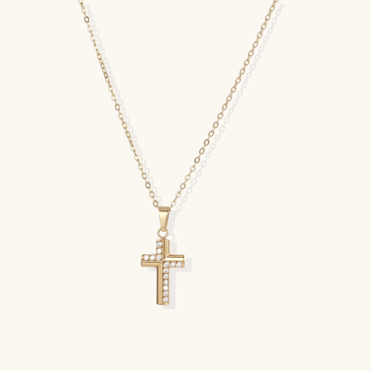 Gold-plated stainless steel cross necklace with crystal embellishments on adjustable chain against light background.