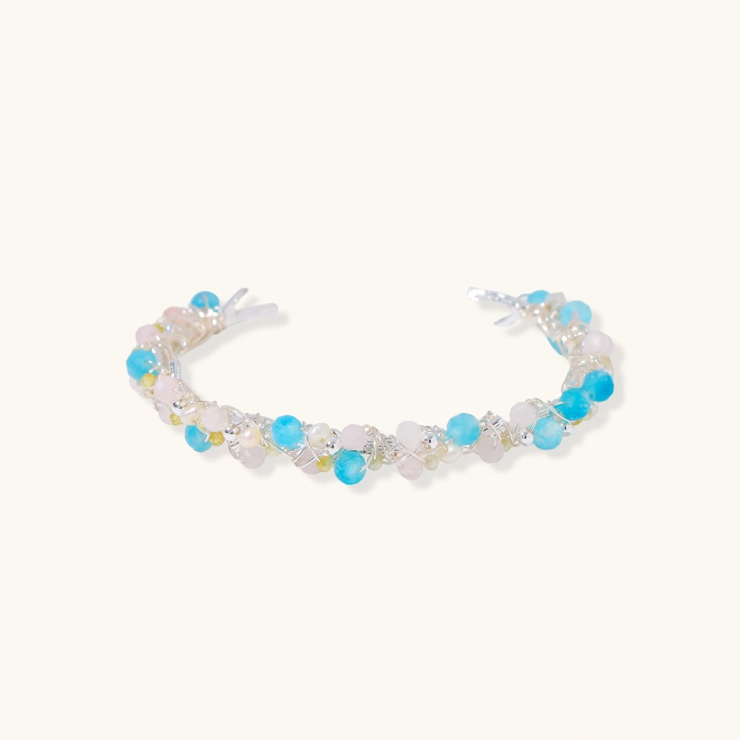 Delicate wire-wrapped bracelet featuring turquoise, rose quartz, freshwater pearls, and zircon on a white background.
