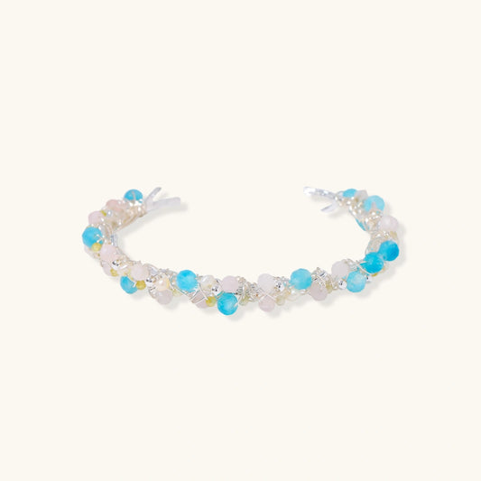 Delicate wire-wrapped bracelet featuring turquoise, rose quartz, freshwater pearls, and zircon on a white background.